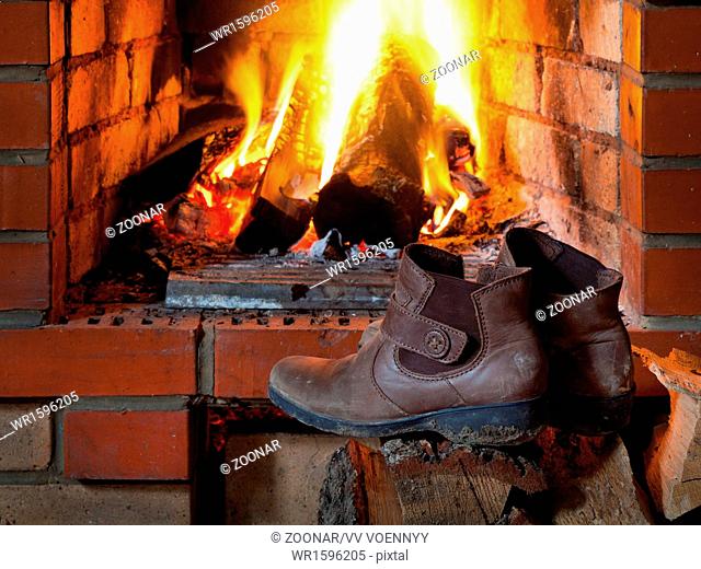 boots are dried near fire in fireplace