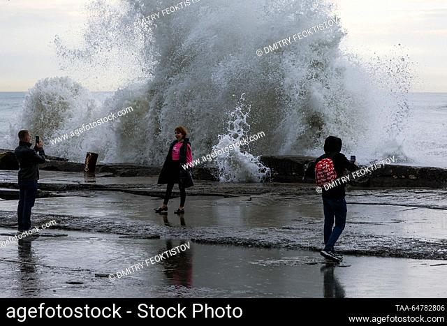 RUSSIA, SOCHI - NOVEMBER 13, 2023: People take pictures as waves smash against the coast during a storm on the Black Sea, in the Adler neighbourhood