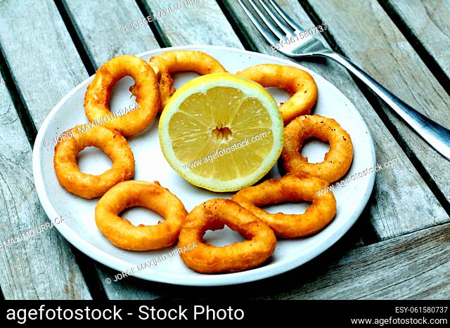 Fried calamari rings with lemon in white plate