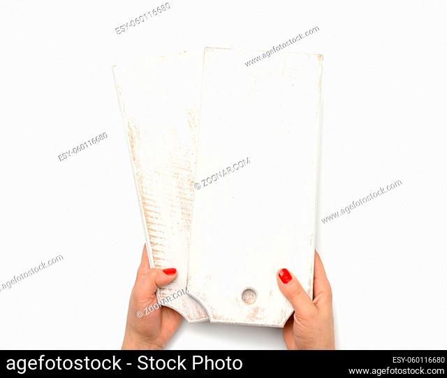 female hand with red manicure holds empty white wooden rectangular kitchen chopping board on white background