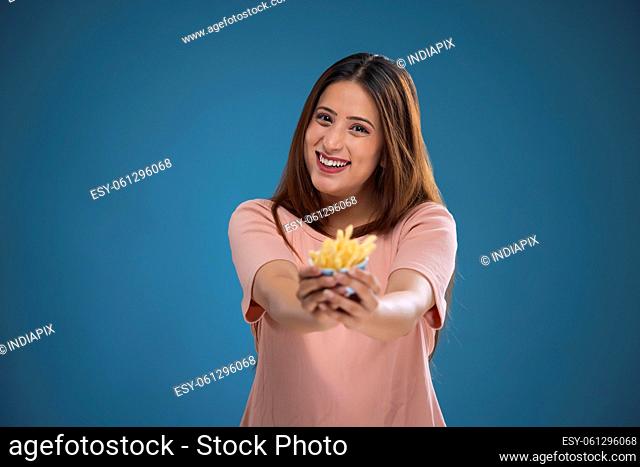 Portrait of a cheerful woman holding french fries