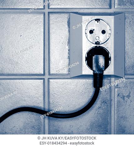 Plugged power cord in wall socket, tinted black and white image