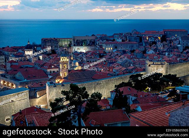 Dubrovnik aerial close up night view after sunset with illuminated fortress wall and dramatic cloudscape, Croatia