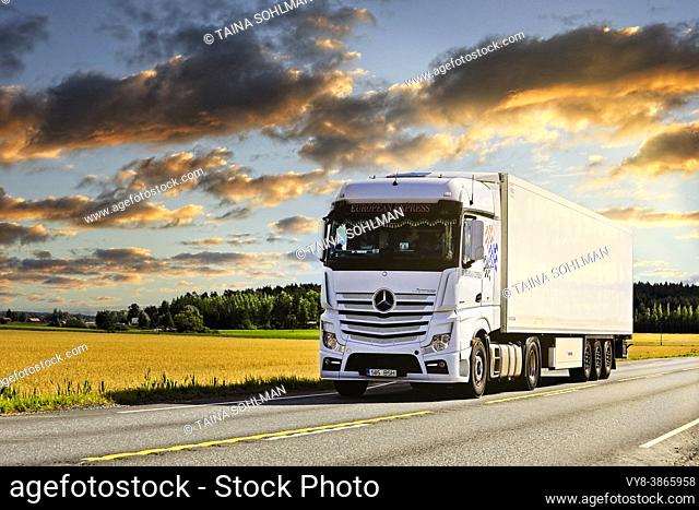White Mercedes-Benz Actros 1845 truck pulls FRC semi trailer on highway 2 under beautiful dusktime sky in the summer. Jokioinen, Finland. Aug 28, 2020