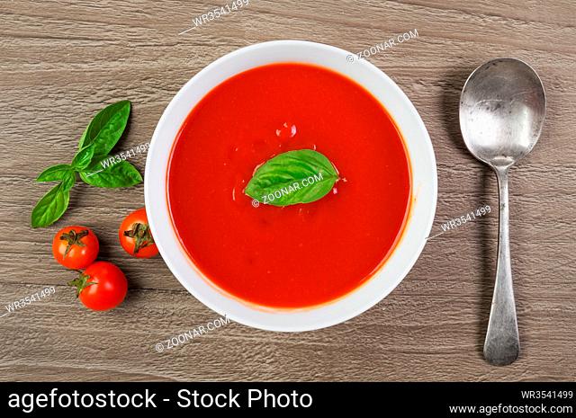 fresh tomato soup in white bowl on wooden background.Top view