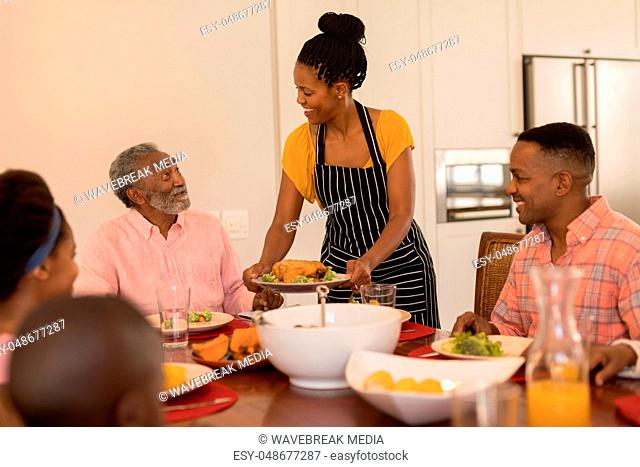 Woman serving food to her family on dining table