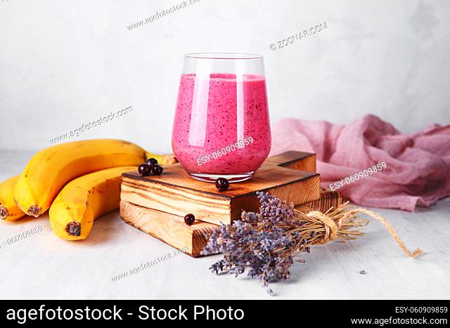 banana berry smoothie in the glass on the wooden serving board. Fresh and healthy breakfast