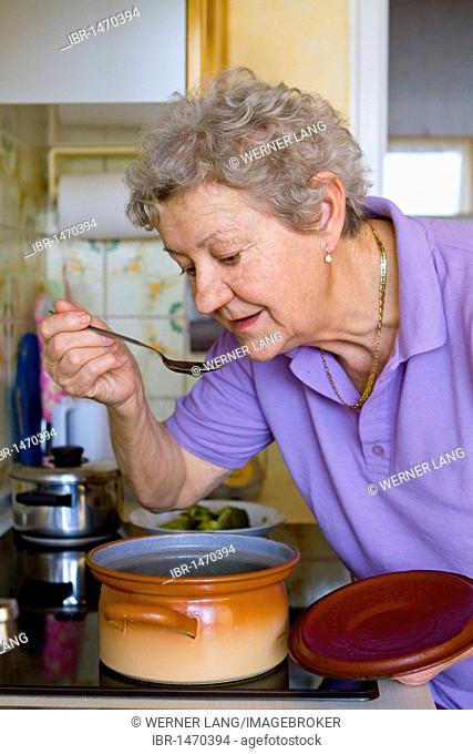 Pensioner tasting soup from a pot