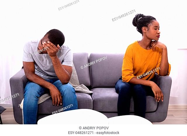 Upset Young African Couple Sitting On Sofa At Home