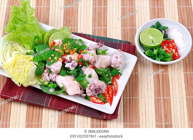 Spicy and sour mixed herb salad with squid wrap minced pork salad is Thai cuisine as sliced lemon grass, kaffir lime leaves, minced red chili, sliced shallots