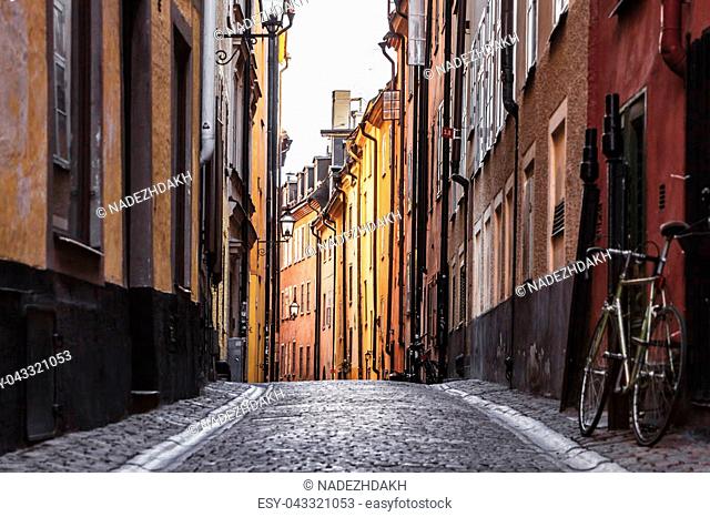 Gamla Stan. Stockholm, Sweden. Colorful Cobbled street in Old Town. Color street with cobblestone road, orange houses, streetlight and bicycle