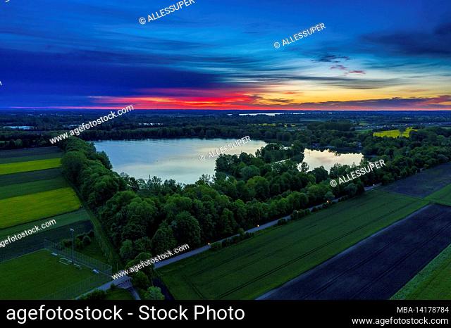 Wonderful aerial morning view over the Feringasee in Unterfoehring with a vibrant red colored sunrise. Wonderful start into a new day