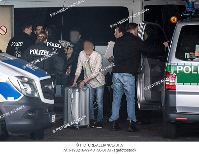18 February 2019, Hessen, Frankfurt/Main: Handcuffed at the airport, one man pushes his suitcase between police officers