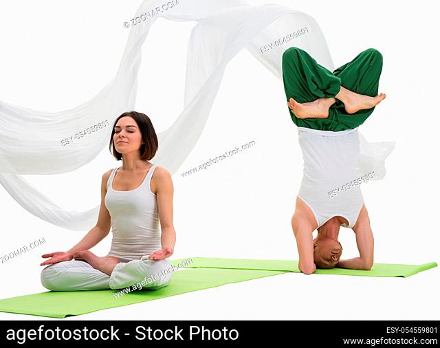 Couple in white sport tshirts and green trousers doing yoga exercises on green mats in studio isolated shot