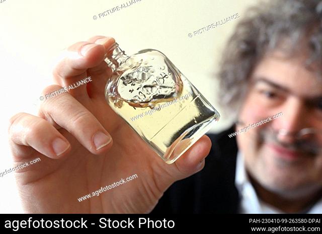 PRODUCTION - 03 April 2023, Baden-Württemberg, Karlsruhe: Perfumer Roland Tentunian shakes a bottle containing alcohol and essential oils during a recipe...