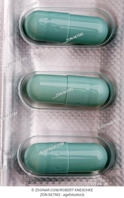 Drei blaue Pillen in ihrer Verpackung