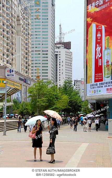 Two women with an umbrella, busy pedestrian zone in the modern city center, Kunming, Yunnan Province, People's Republic of China, Asia