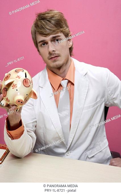 Portrait of a young man holding piggy bank