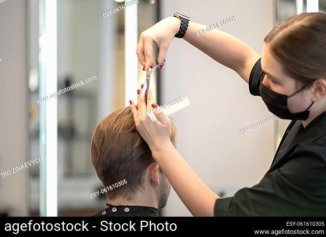 Haircut. Close up picture of females hands with scissors cutting hair