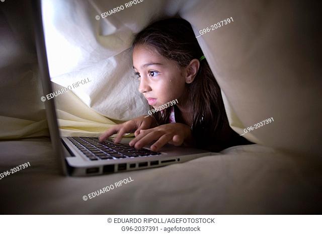 girl under the covers with a laptop