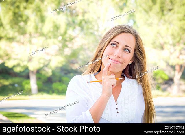 Contemplative Young Woman With Pencil Outdoors at the Park