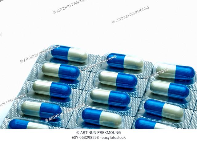 Blue-white capsule pills in blister pack isolated on white background with copy space for text. Antibiotics drug resistance and antimicrobial drug use with...