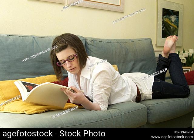 Girl lying on a sofa, reading a magazine