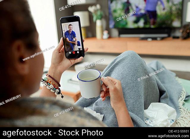Sick woman video chatting with doctor on smart phone screen at home