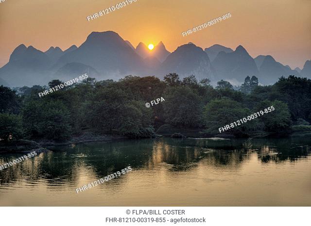 View of limestone karst formations along river at sunset, Li River, Guilin, Guangxi Zhuang Autonomous Region, China, October