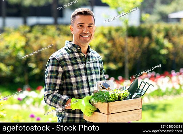 happy man with tools in box at summer garden