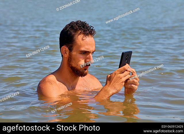 Using smartphone obsessively at the beach on vacation