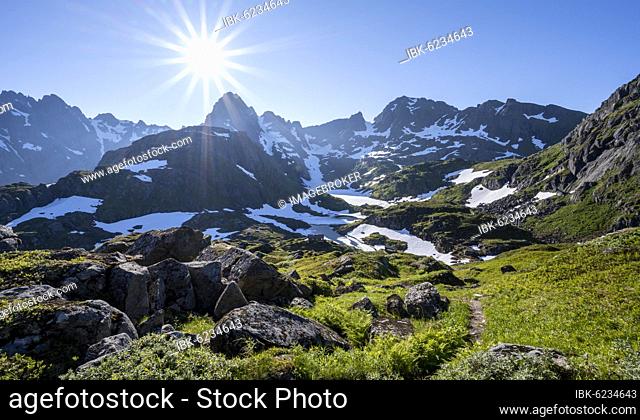 Hiking trail, sun shining on mountains with snow, mountain range at Trollfjord Hytta, at Trollfjord, Lofoten, Nordland, Norway, Europe