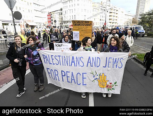 19 November 2023, North Rhine-Westphalia, Cologne: Participants in a Jewish-Palestinian peace demonstration hold a banner reading ""Palestinians and jews for...