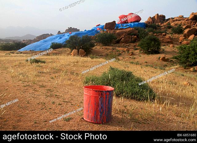 Empty paint bucket in front of the freshly painted rocks near Tafraoute, Antiatlas Morocco