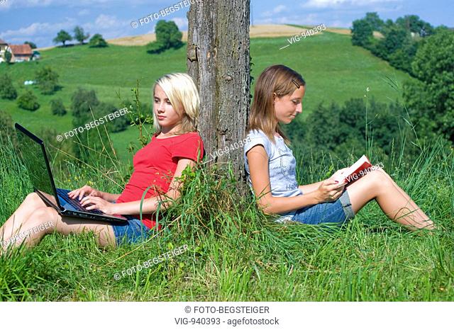 two teenage girls ouside using laptop and reading a book. - 14/07/2008