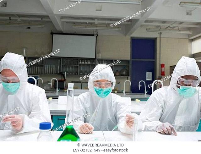 Chemists in protective suits adding liquid to petri dishes in the lab