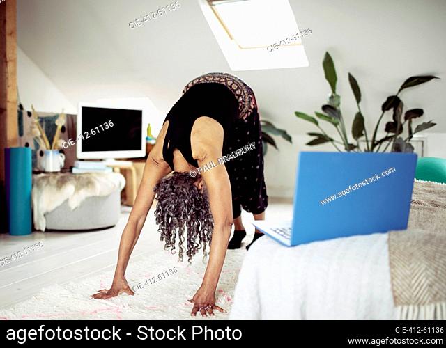 Senior woman practicing yoga online at home