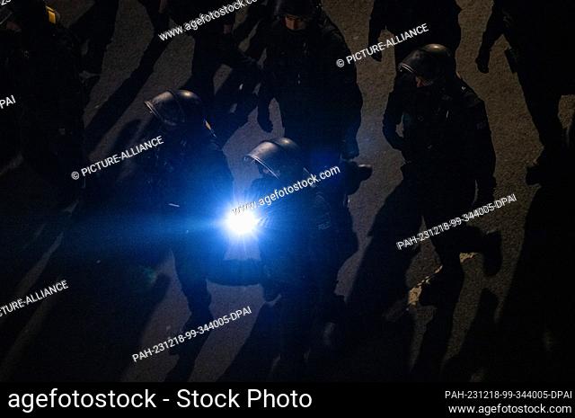 18 December 2023, Saxony, Dresden: Police officers accompany a demonstration by the right-wing extremist movement Pegida, shining a flashlight