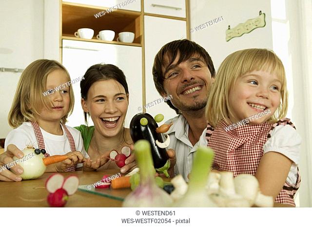Familiy in kitchen, playing with children