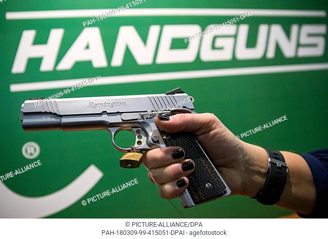 09 March 2018, Germany, Nuremberg: A woman holding a handgun by the American manufacturer Remington at the IWA OutdoorClassics trade show for hunting