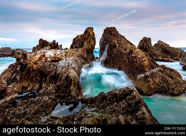 Ocean waves force their way through the gap in these dramatic jagged rocks