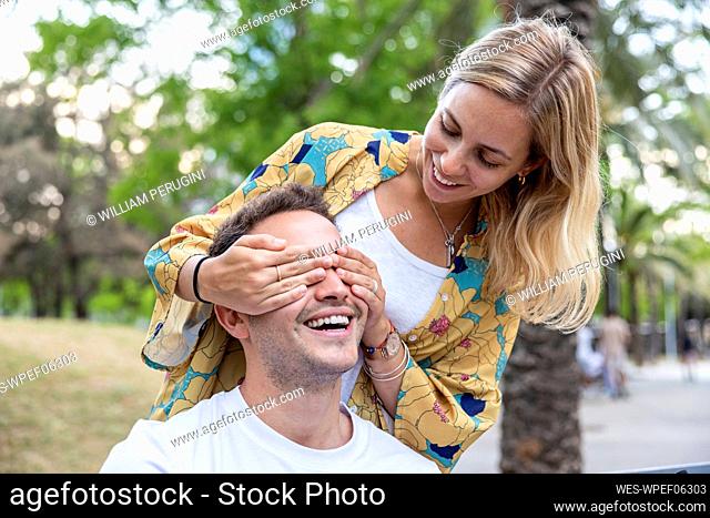 Smiling woman covering eyes of boyfriend at park