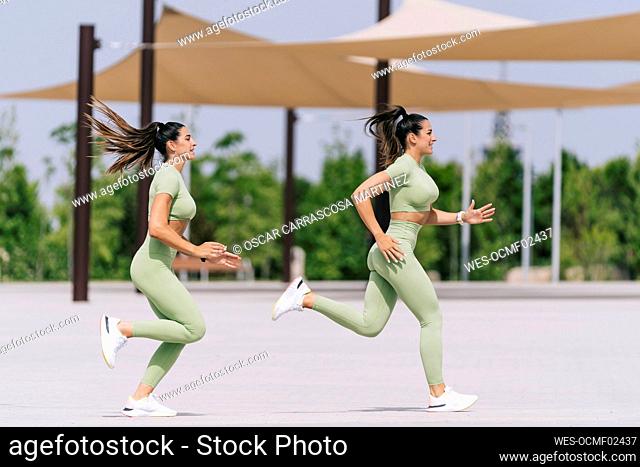 Twin sisters running on footpath