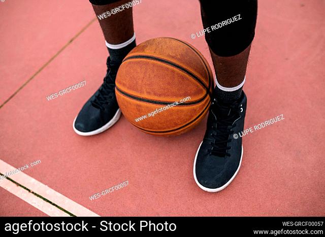 Basketball between feet of basketball player
