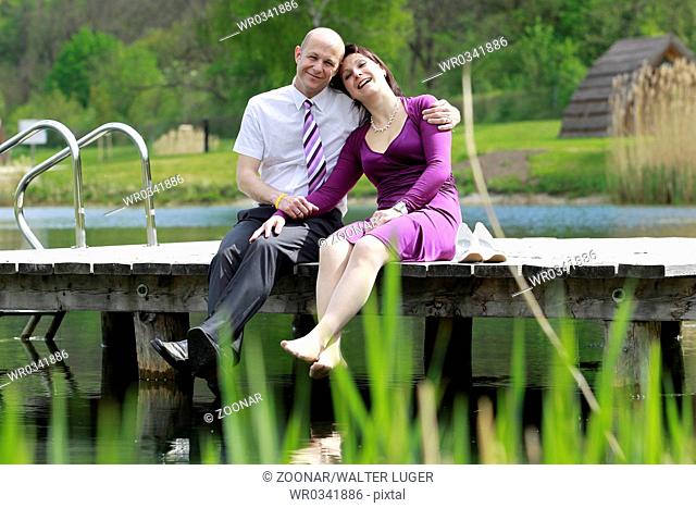 A couple sitting on a dock on the lake