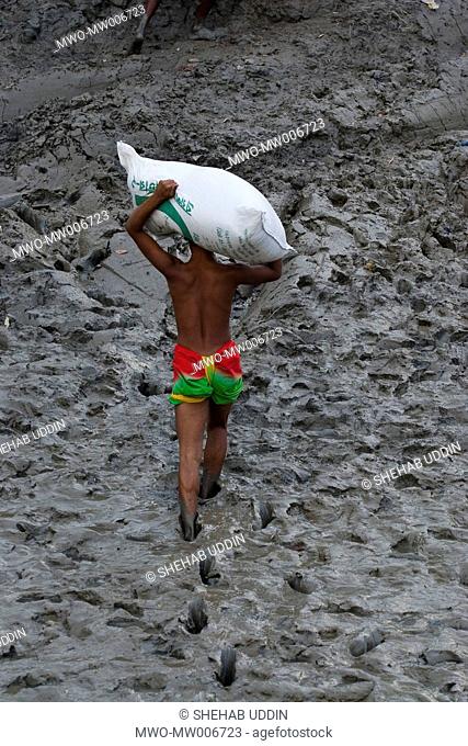 A young man unloads rice from ferry launch in Mathbari, a far-off village in the Sundarbans Mathbari, Kaira, Bangladesh May 03, 2007