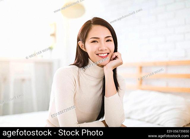 Young beautiful woman smiling and sitting on bed at home