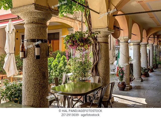 foreshortening of stone columns of old covered walkway in historical touristic village, shot on bright summer day at Orta San Giulio, Novara, Cusio, Italy