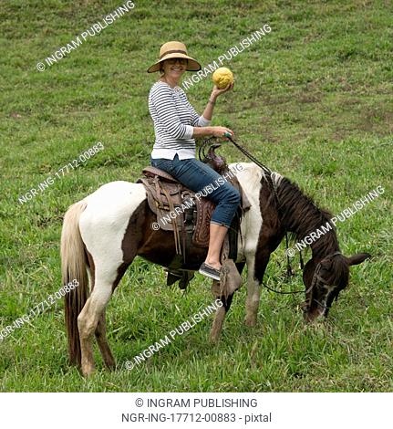 Woman horseback riding in a field, Finca El Cisne, Honduras