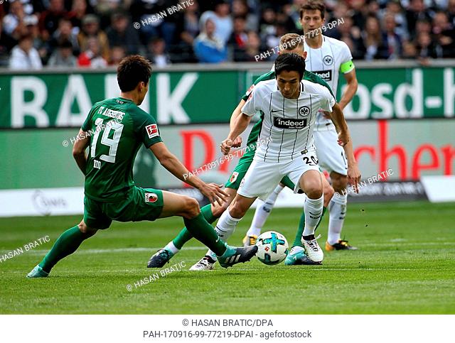Frankfurt's Makoto Hasebe (M) in action against Augsburg's Ja-Cheol Koo (L) und Alfred Finnbogason during the German Bundesliga soccer match between Eintracht...